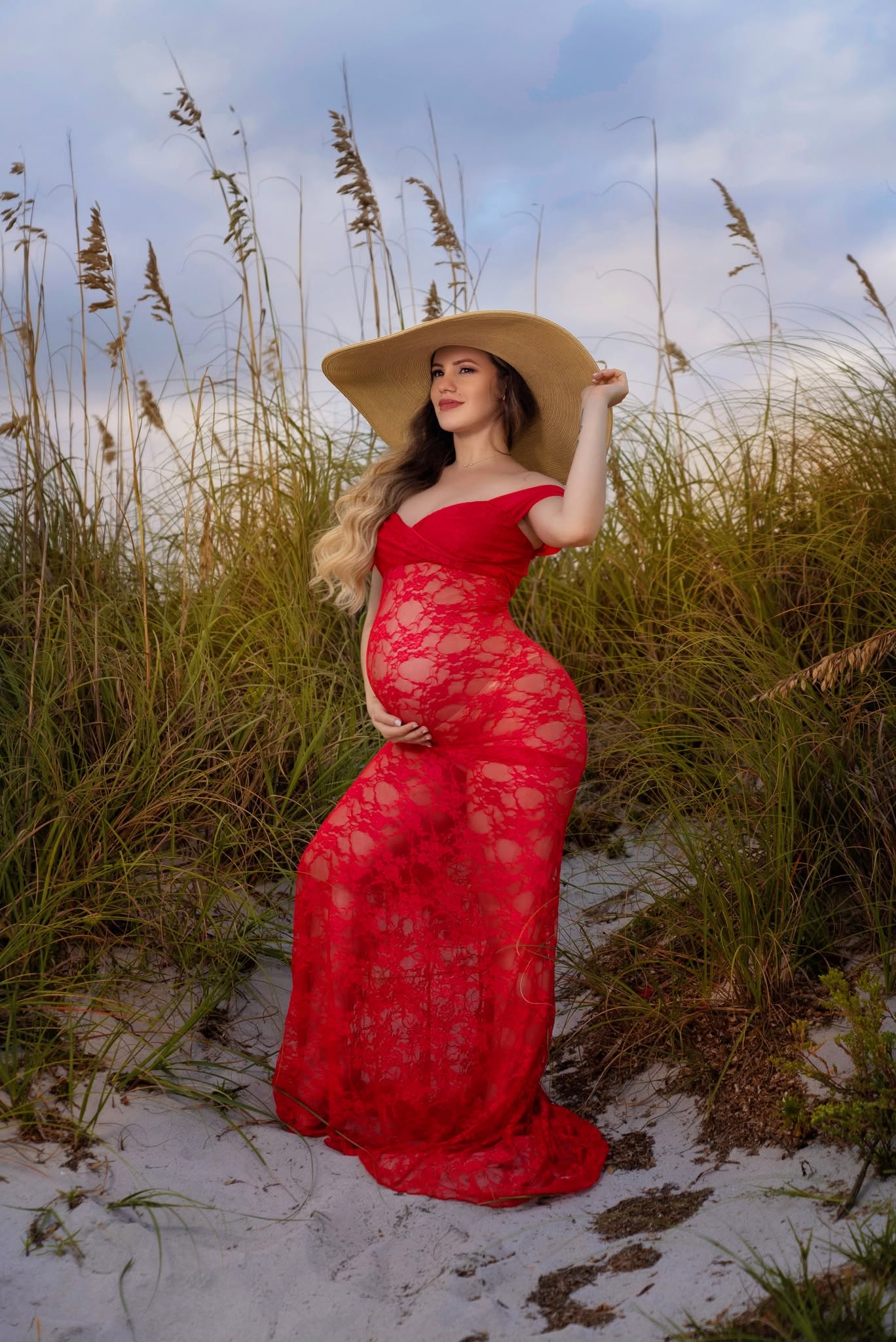 Maternidad en playa con vestido rojo y sombrero