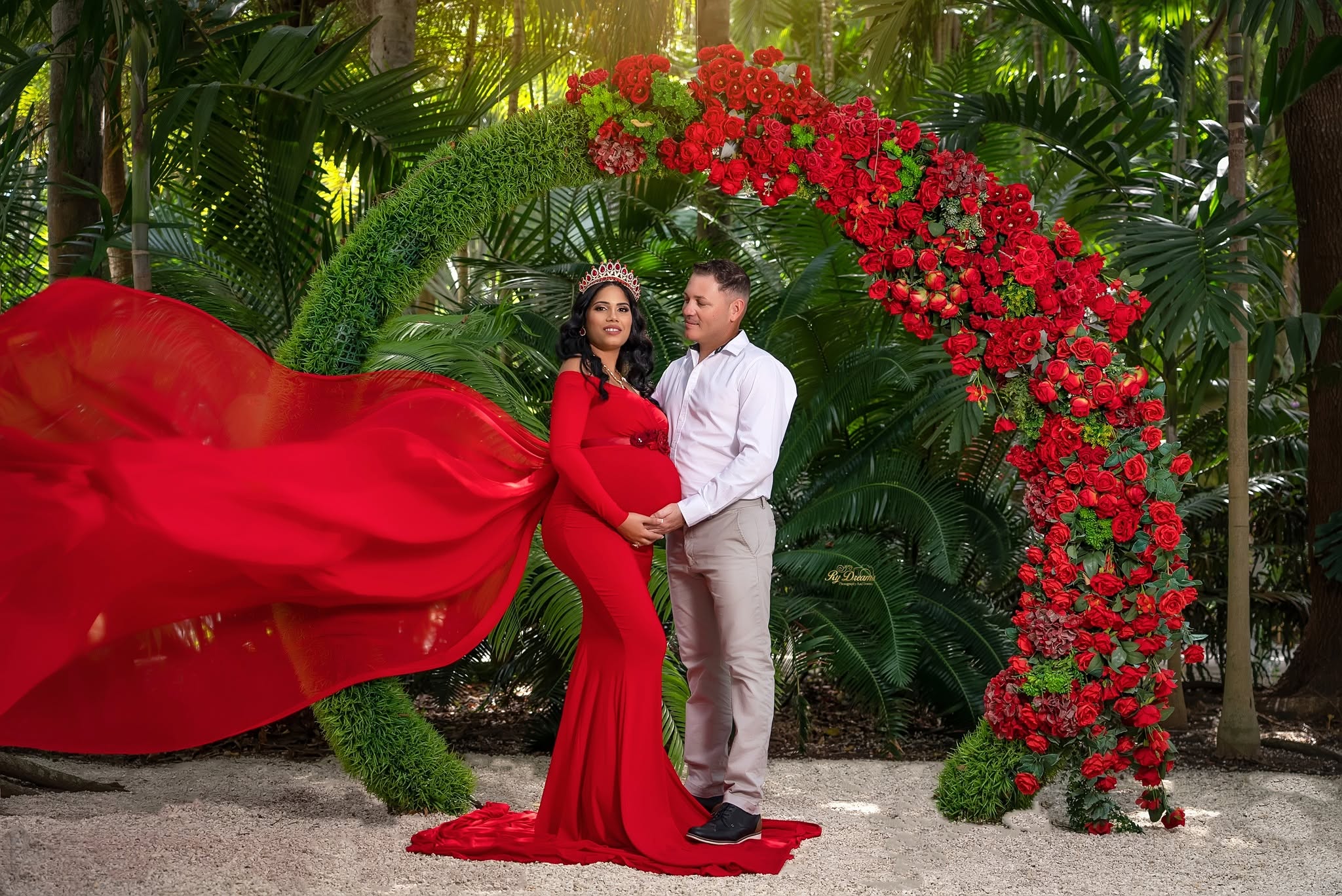Sesión de maternidad con pareja en arco floral rojo